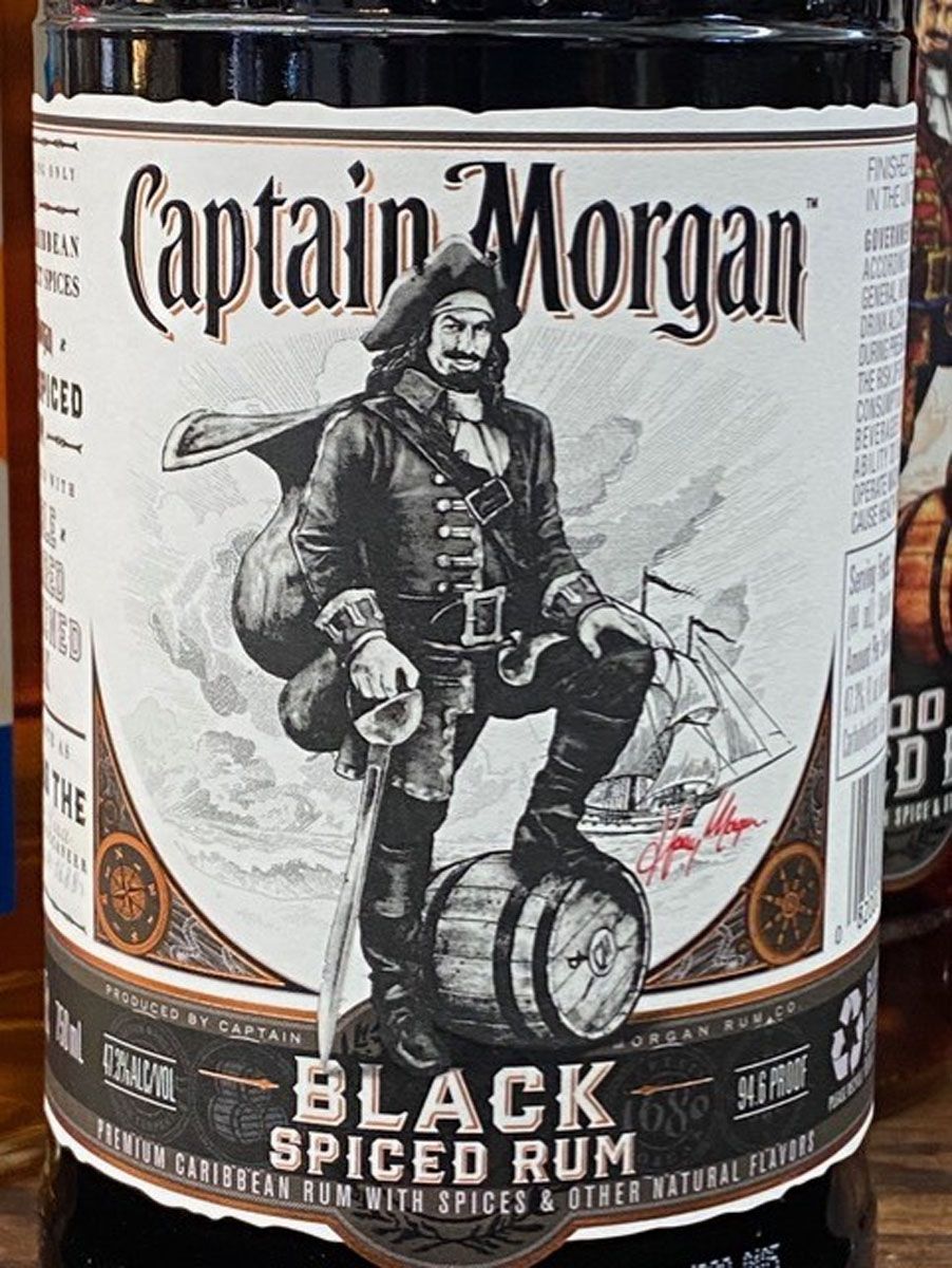 A bottle of captain morgan black spiced rum is sitting on a wooden table.