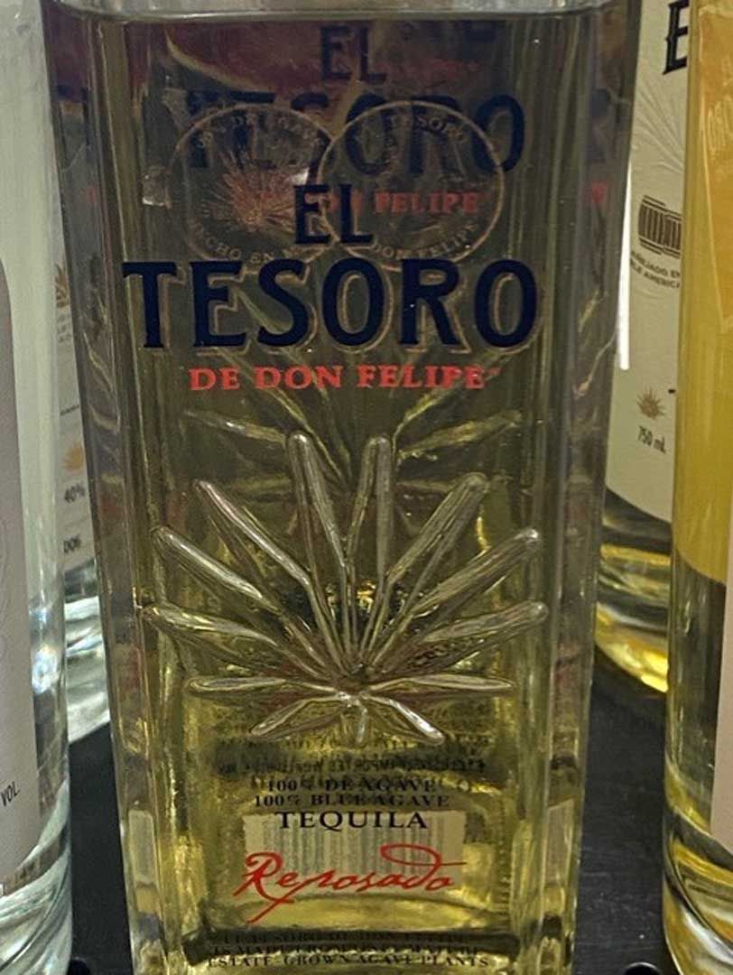 A bottle of tesoro de don felipe tequila is sitting on a table.