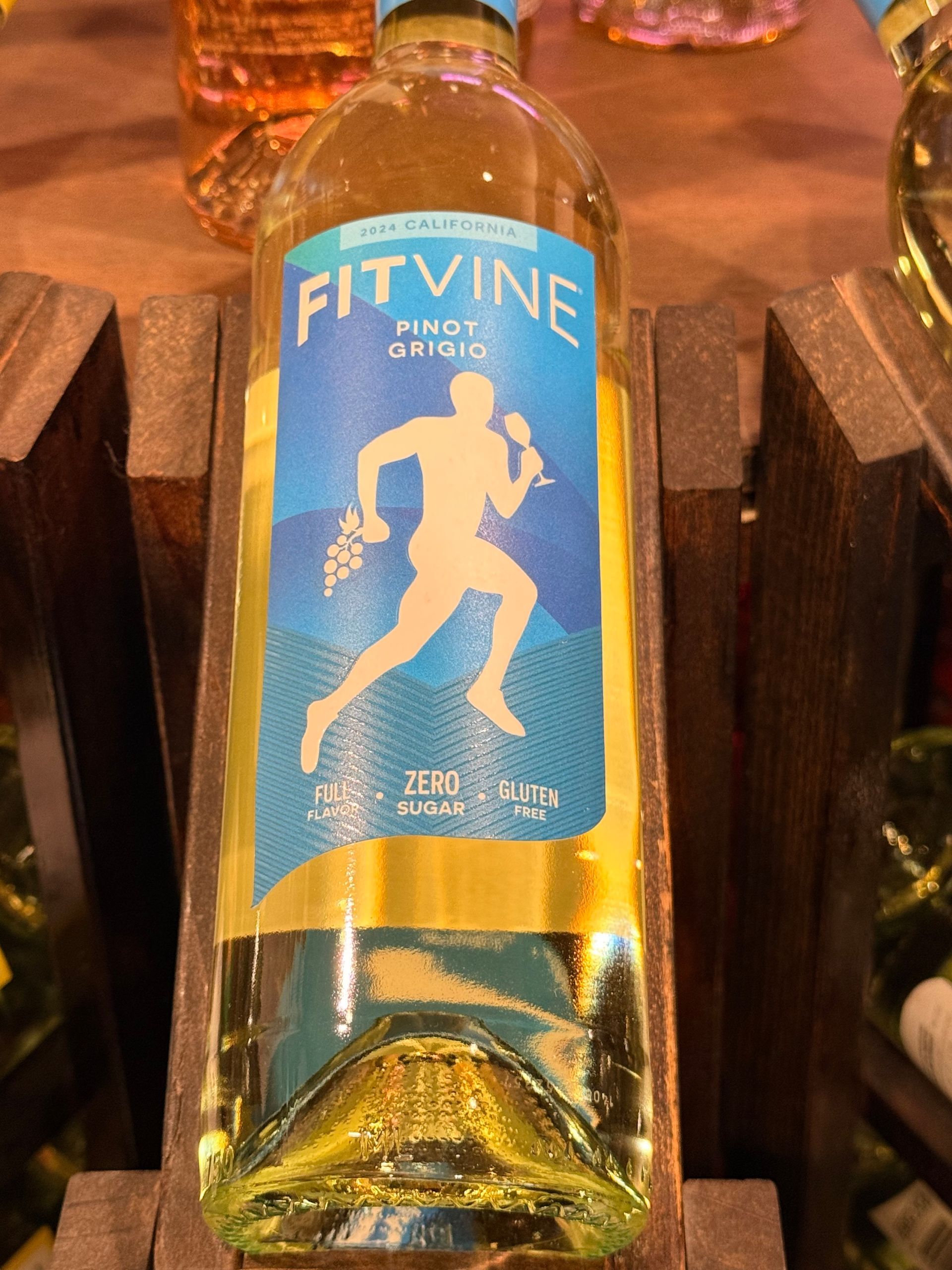 Bottle of Threadcount Quilt wine, gold label with green starburst design, in a wooden wine rack.