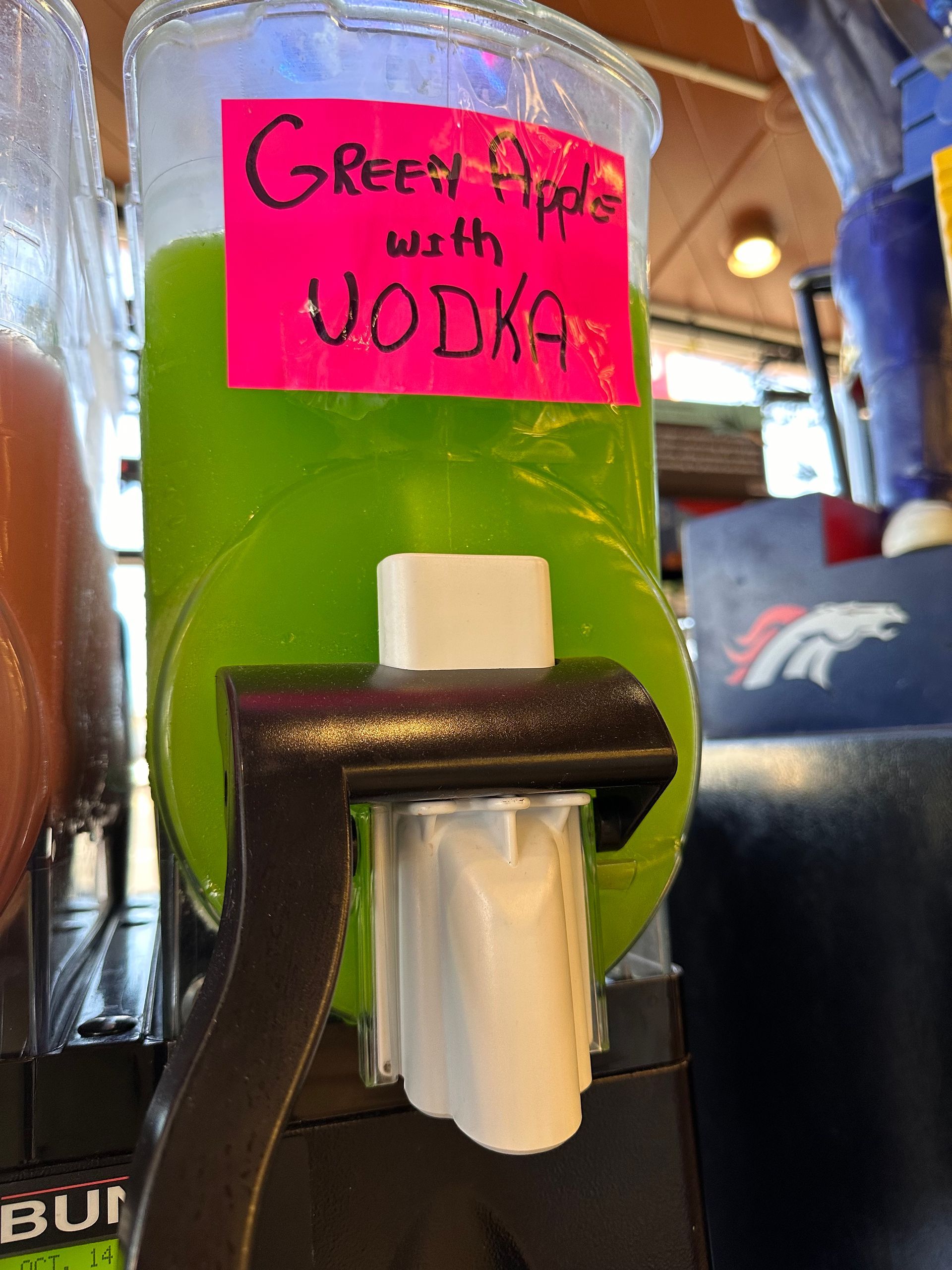 A drink dispenser with green apple vodka in it