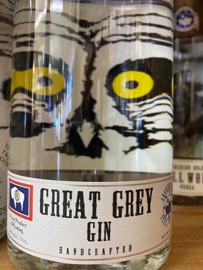 A bottle of great grey gin is sitting on a wooden table.