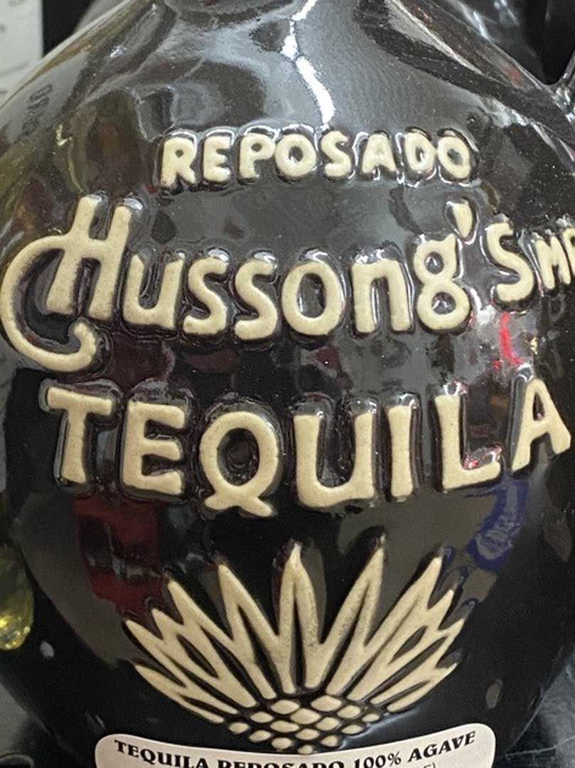 A bottle of hussong 's tequila is sitting on a table