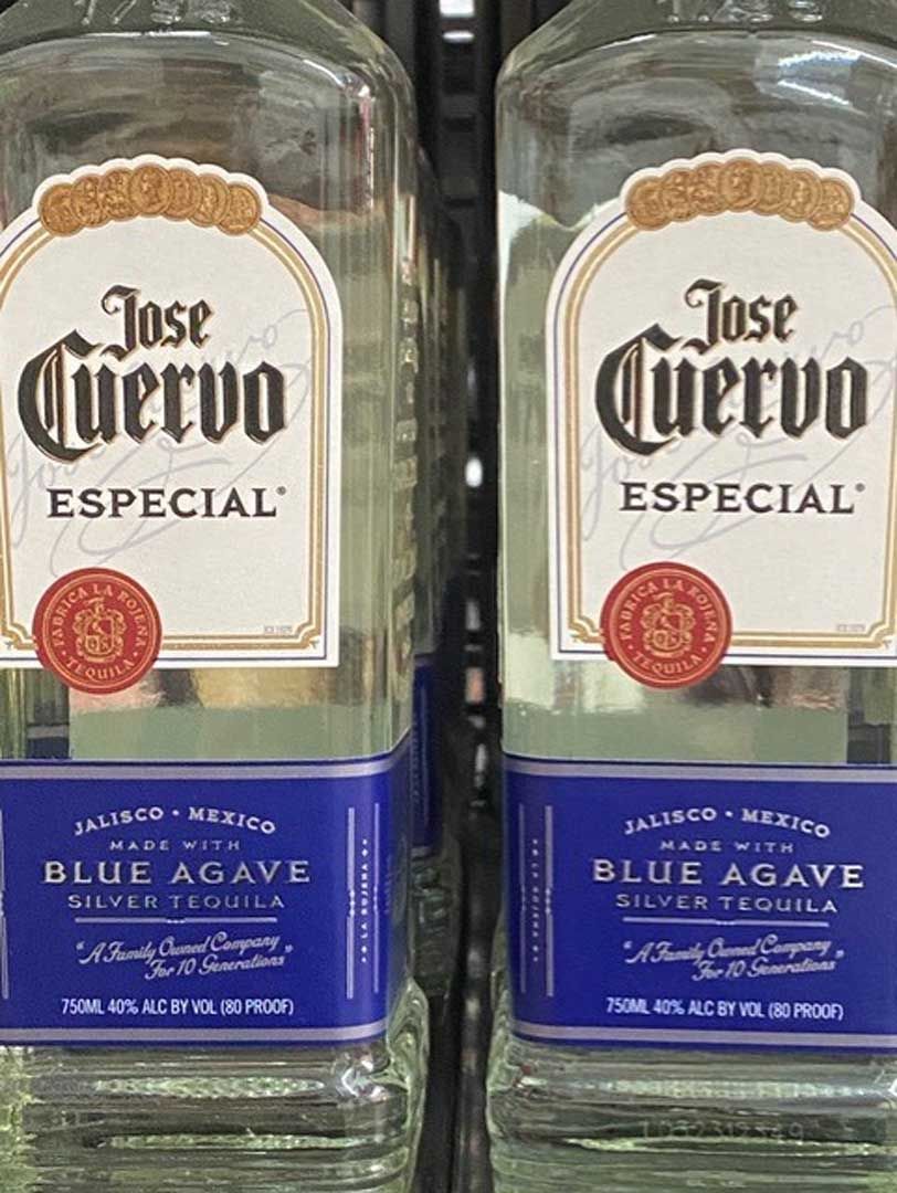 Two bottles of jose cuervo especial blue agave tequila are sitting on a shelf.