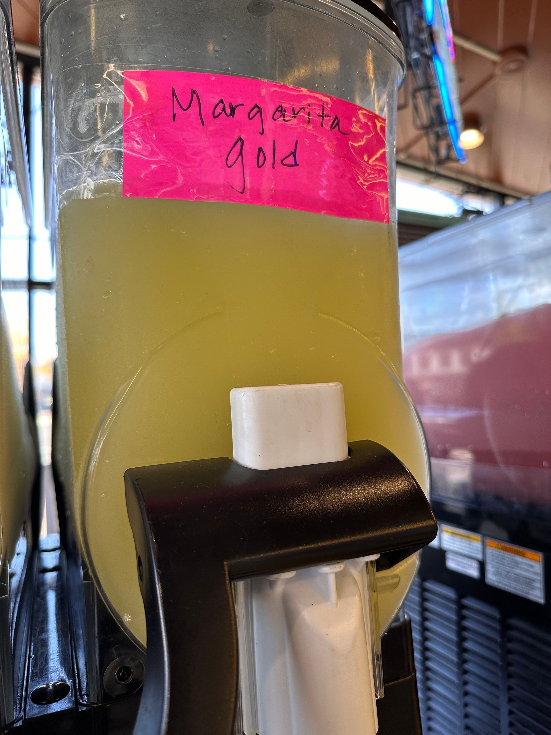 A bottle of margarita gold is being dispensed from a machine