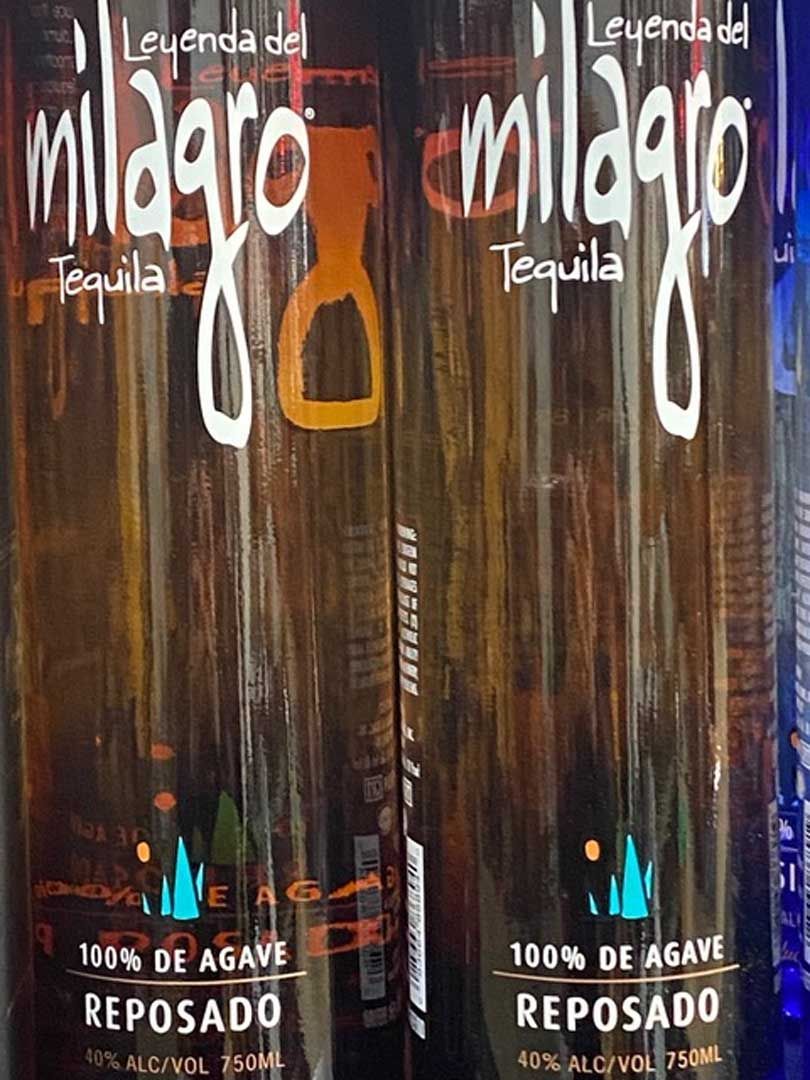 Two bottles of milagros tequila are sitting next to each other.