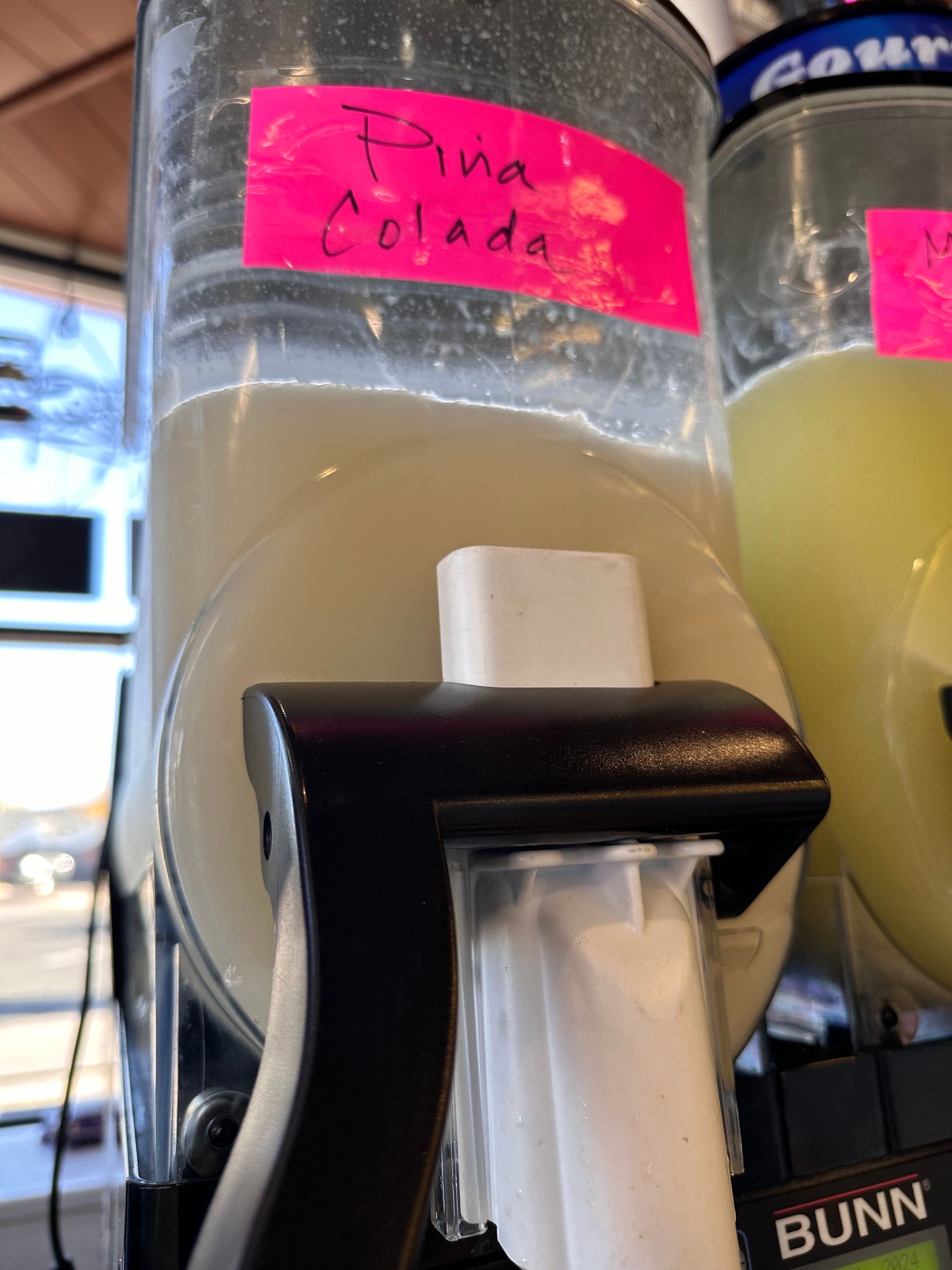 A bottle of pina colada sits next to a bunn machine