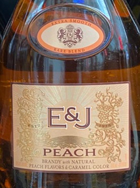 A bottle of e & j peach brandy with natural peach flavors and caramel color