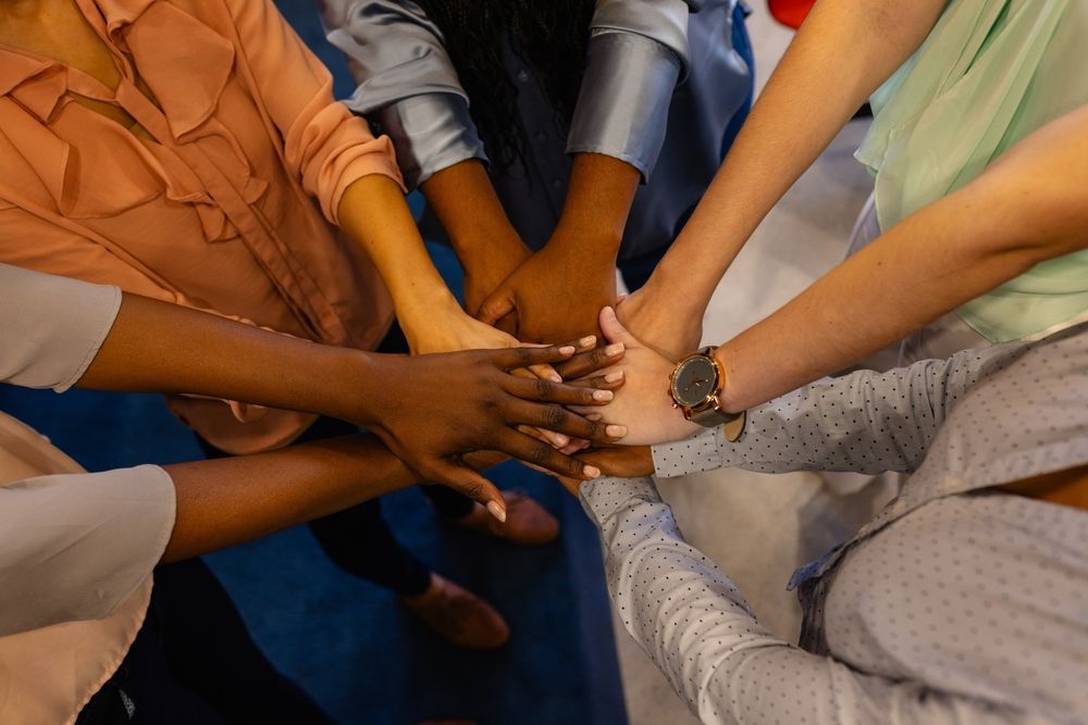 A group of people are putting their hands together in a circle.