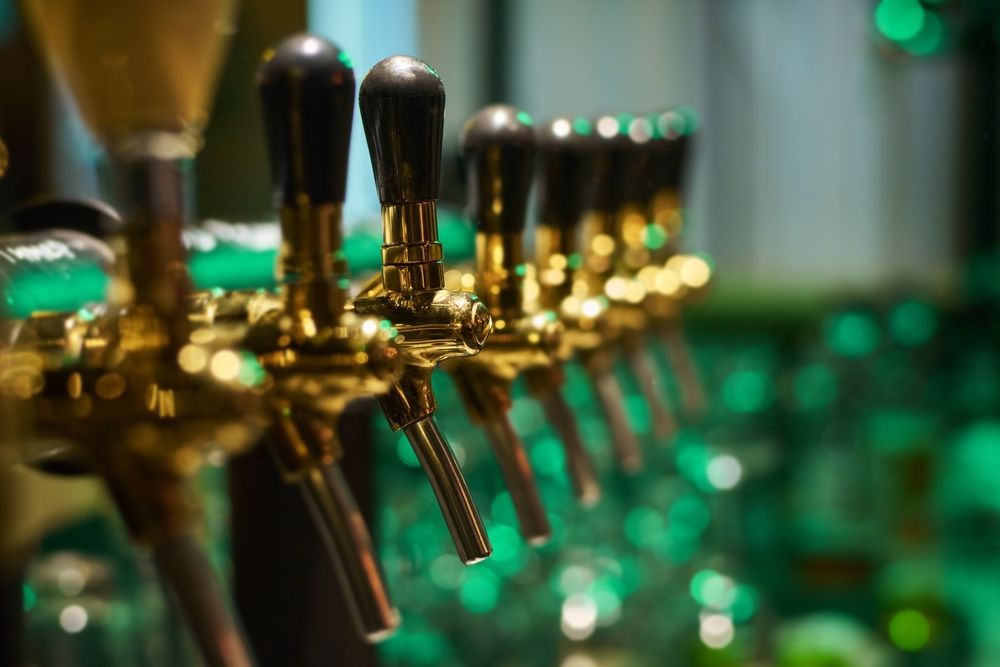 A close up of a row of beer taps in a bar.