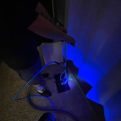 Person holding a flexible, blue, illuminated light fixture in a dark room.