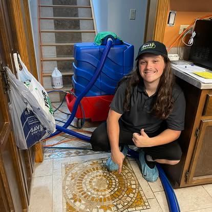 Young person cleaning tile floor with machine, smiling, thumbs up. Blue and red cleaning machine, interior, stairs.
