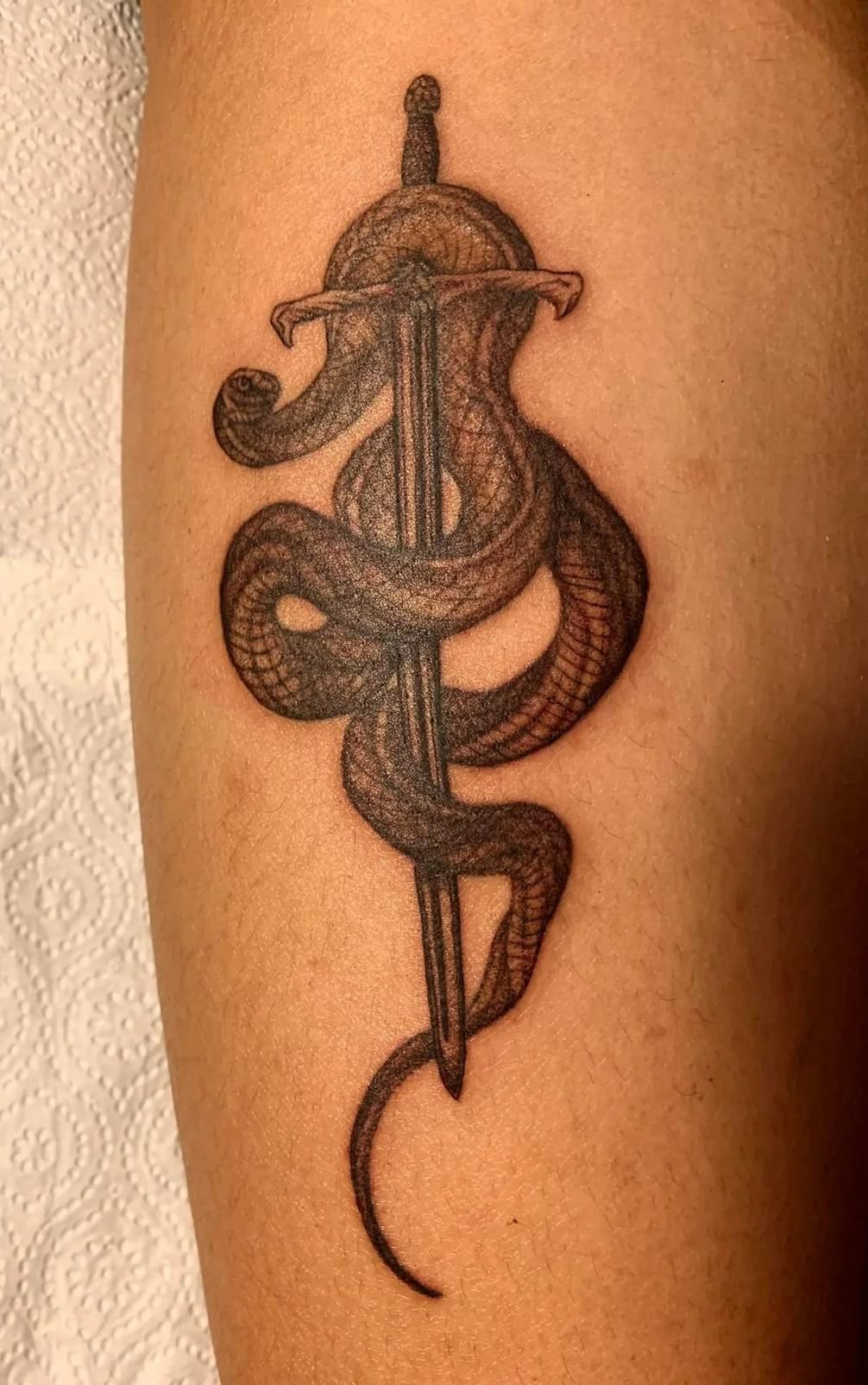 A Detailed Tattoo of a Caduceus Symbol, Featuring two Snakes Entwined Around a Winged staff, Inked on a Person's arm — Thaiger Ink in Holloways Beach, QLD