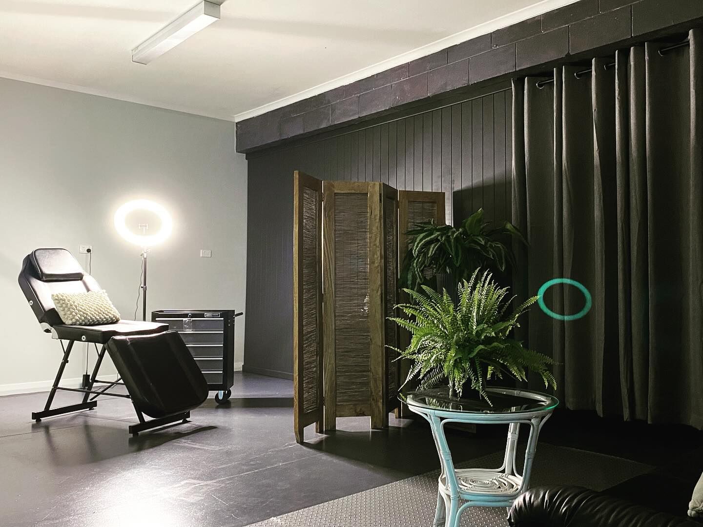 Tattoo Studio Interior with Chair, Ring Light, Screen, Plants, and Black and Gray Decor — Thaiger Ink In Holloways Beach, QLD