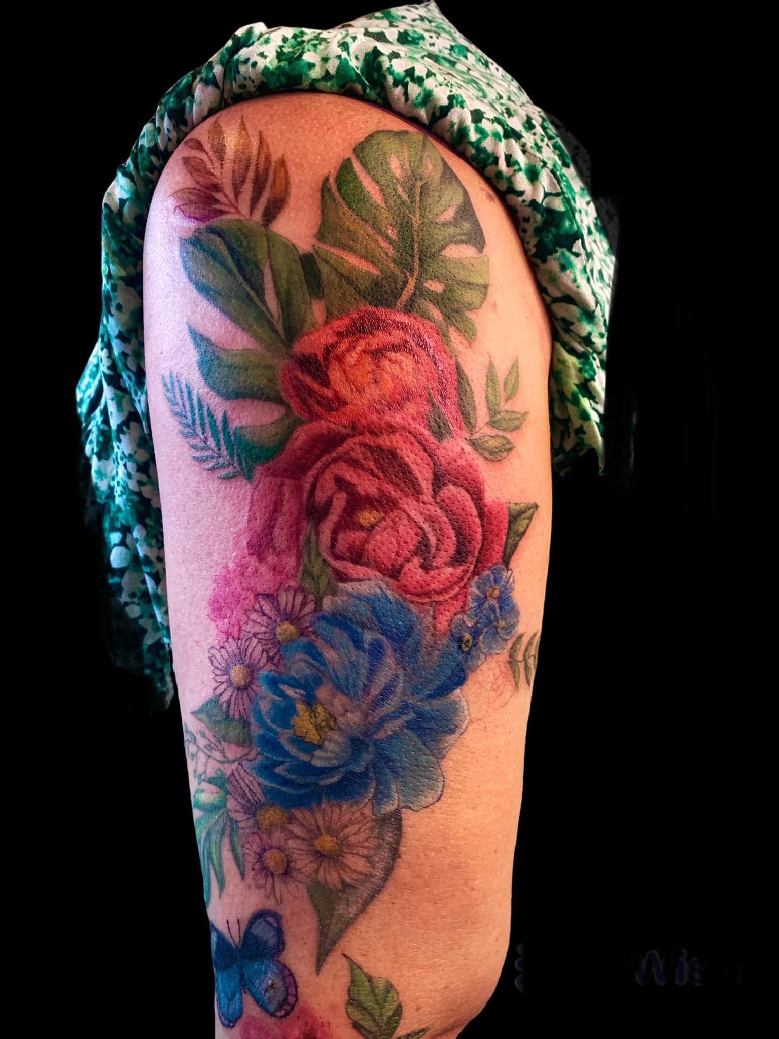 Tattoo of A Green and Blue Bow on A Person's Upper Arm, with Pink Clothing in The Background — Thaiger Ink In Holloways Beach, QLD