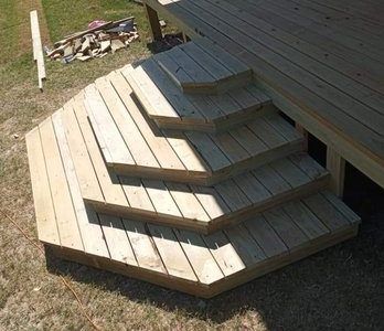 Wooden deck stairs with a hexagonal base, leading to a larger wooden deck.