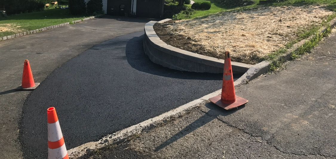 Two orange and white traffic cones are sitting on the side of a road.