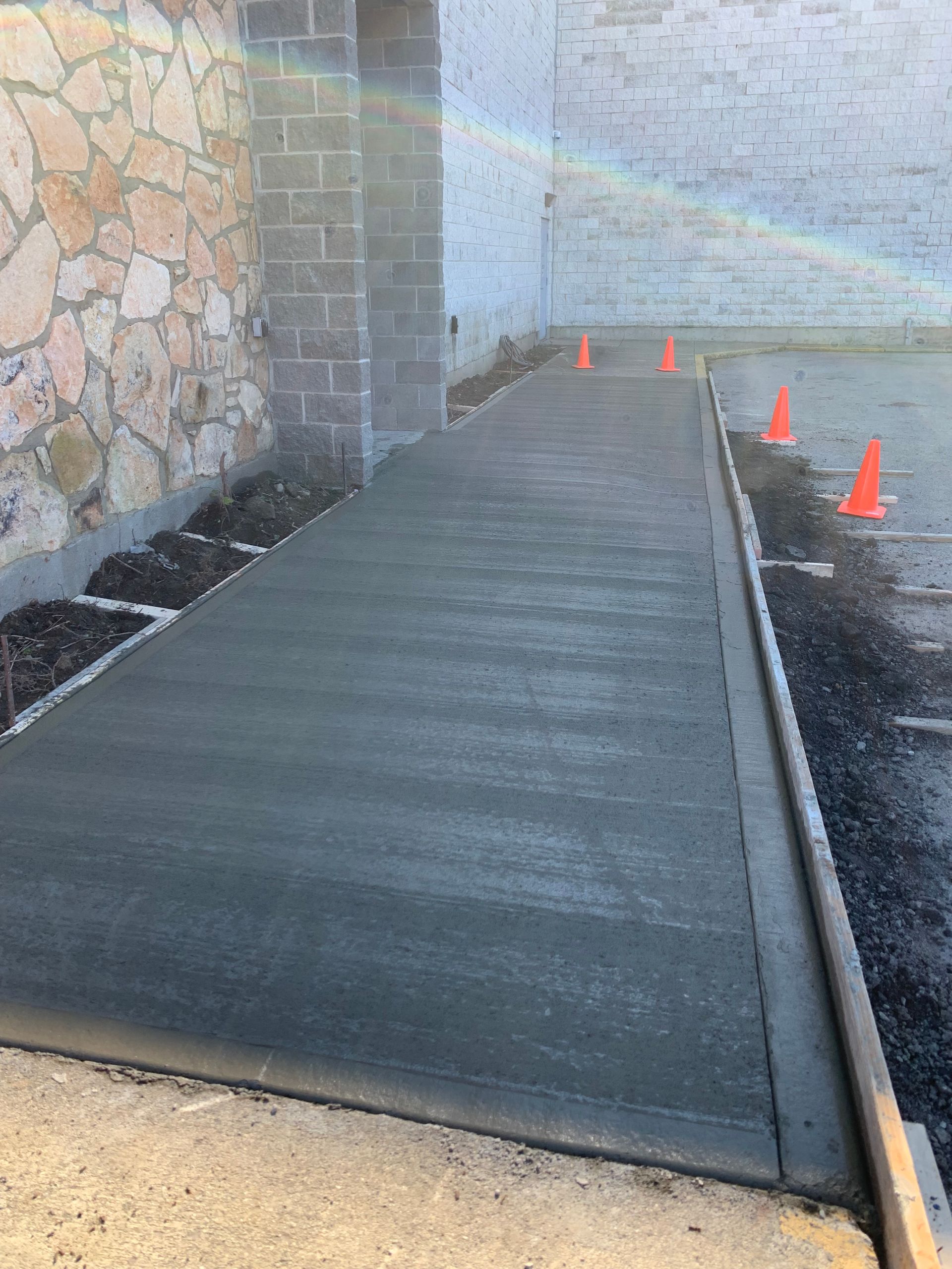 A concrete walkway is being built in front of a stone wall.