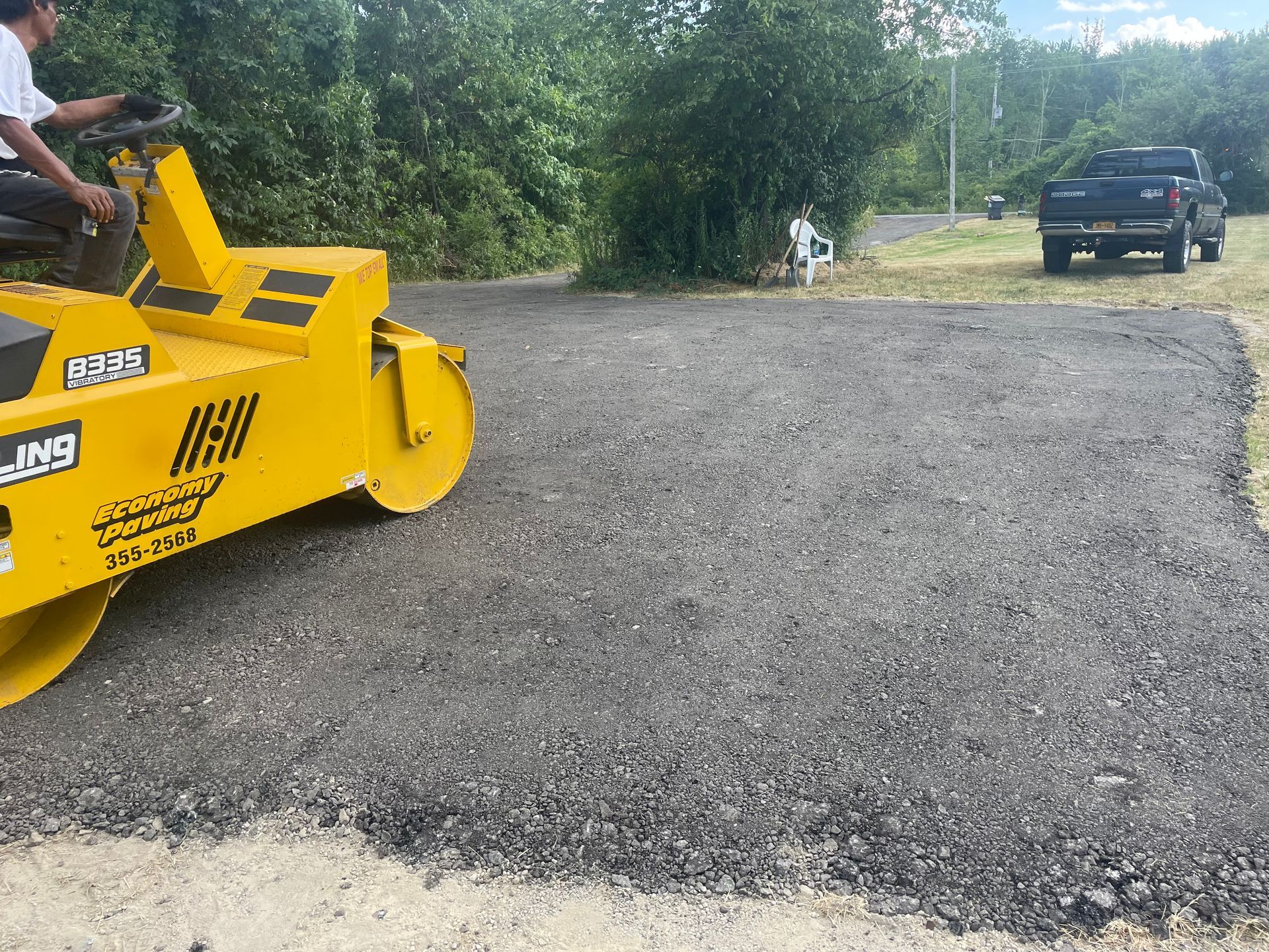 A man is driving a yellow roller on a road.
