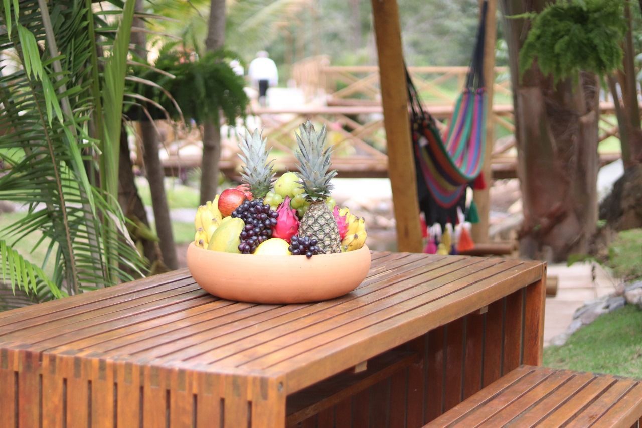 Uma mesa de madeira com uma tigela de frutas sobre ela.