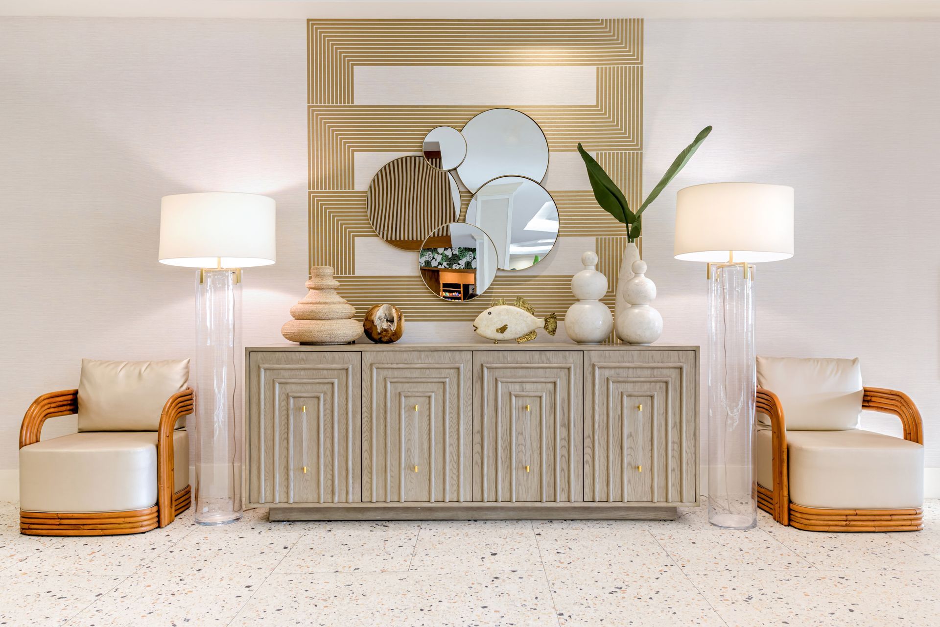 A living room with a dresser , chairs , lamps and a mirror.