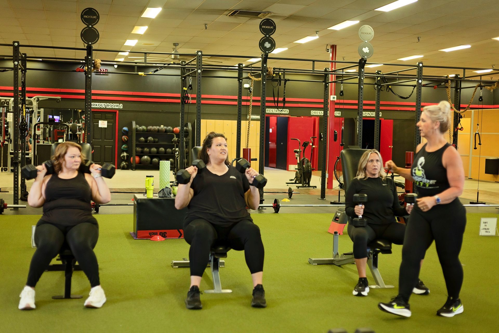 A group of women are lifting dumbbells in a gym.