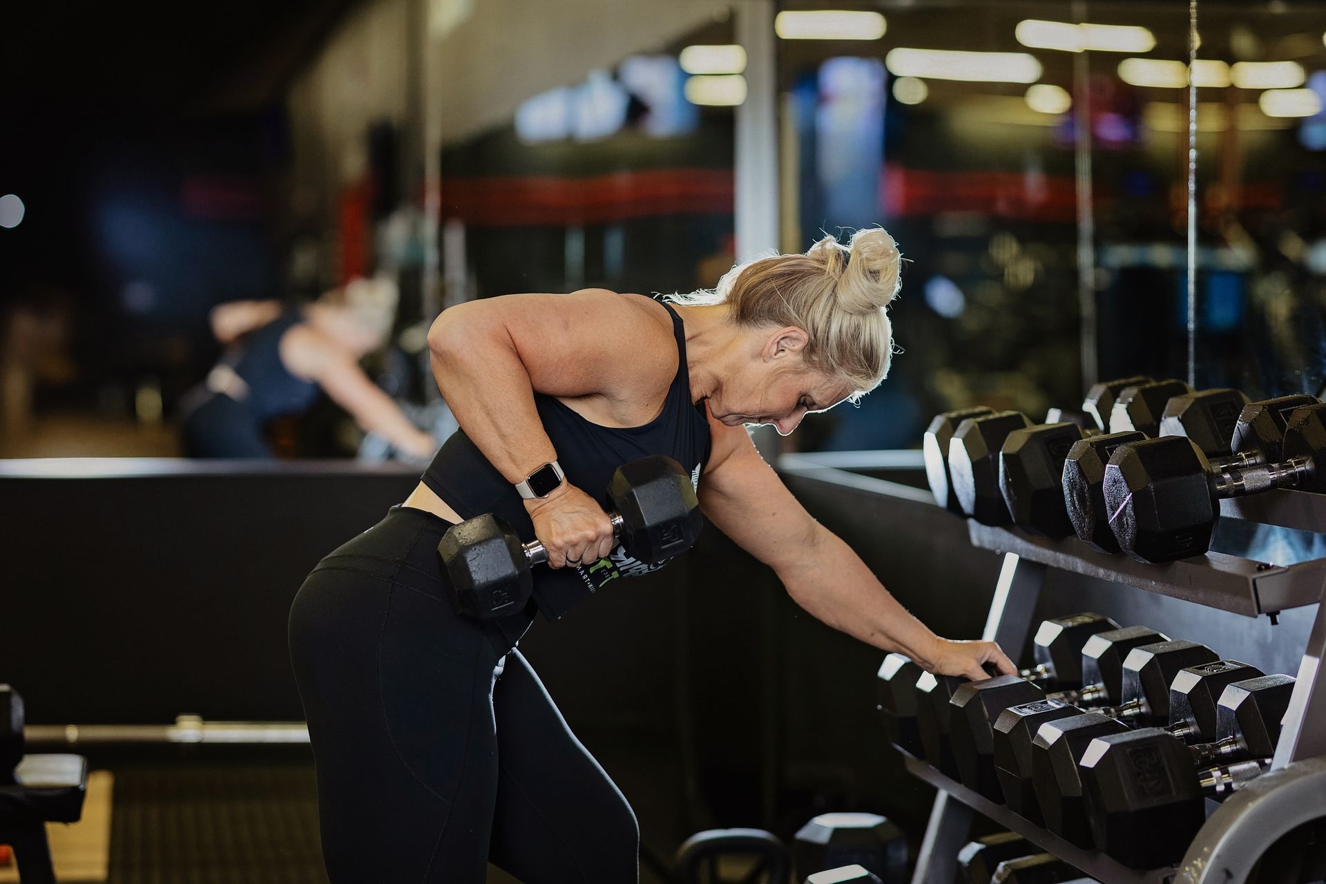 A woman is lifting a dumbbell in a gym.