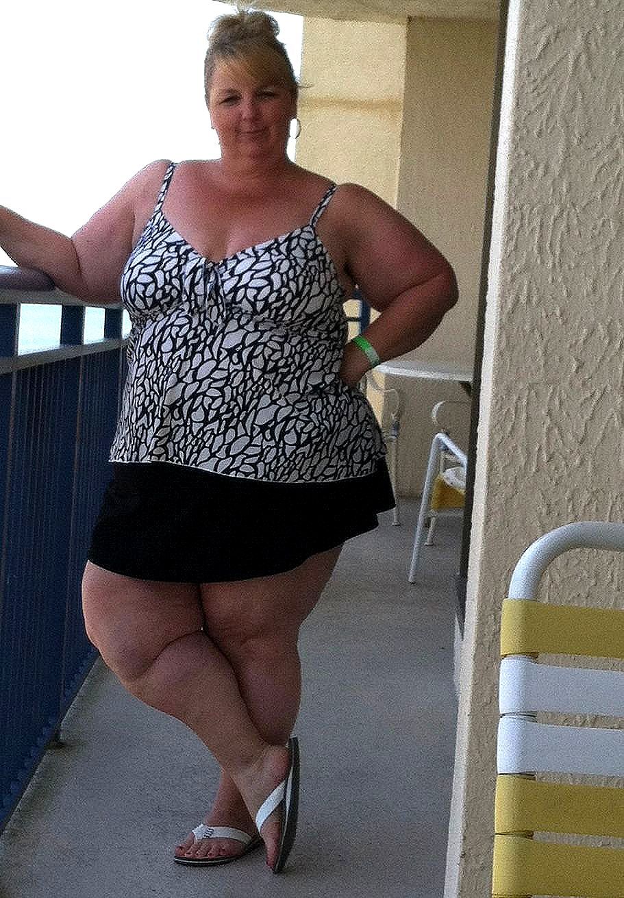 A woman in a bathing suit is standing on a balcony.