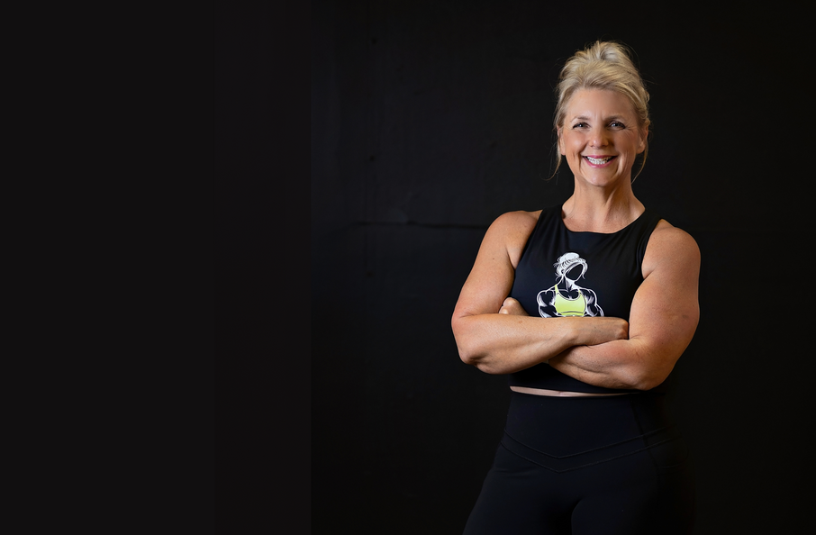 Tracy T is standing with her arms crossed in front of a black wall.