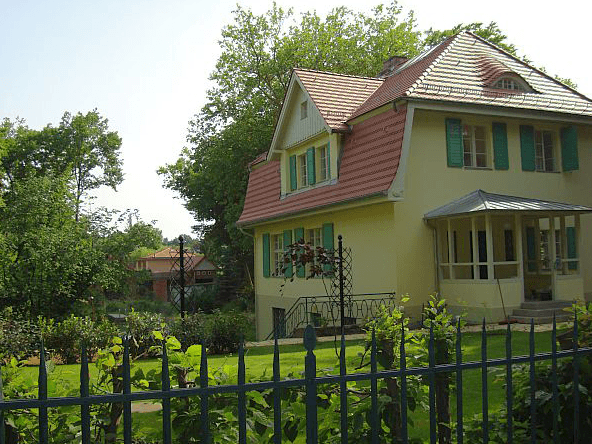 Ein gelbes Haus mit grünen Fensterläden und einem roten Dach