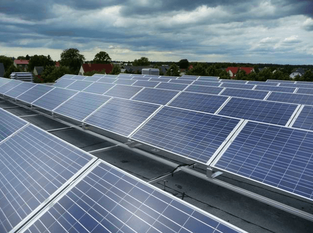 Eine Reihe von Sonnenkollektoren auf einem Dach mit einem bewölkten Himmel im Hintergrund