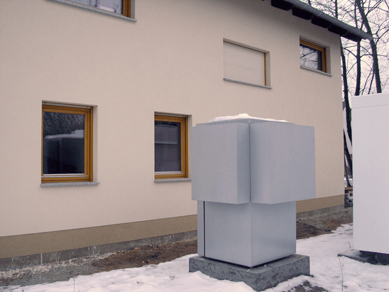 Ein weißes Gebäude mit einem grauen Kasten davor