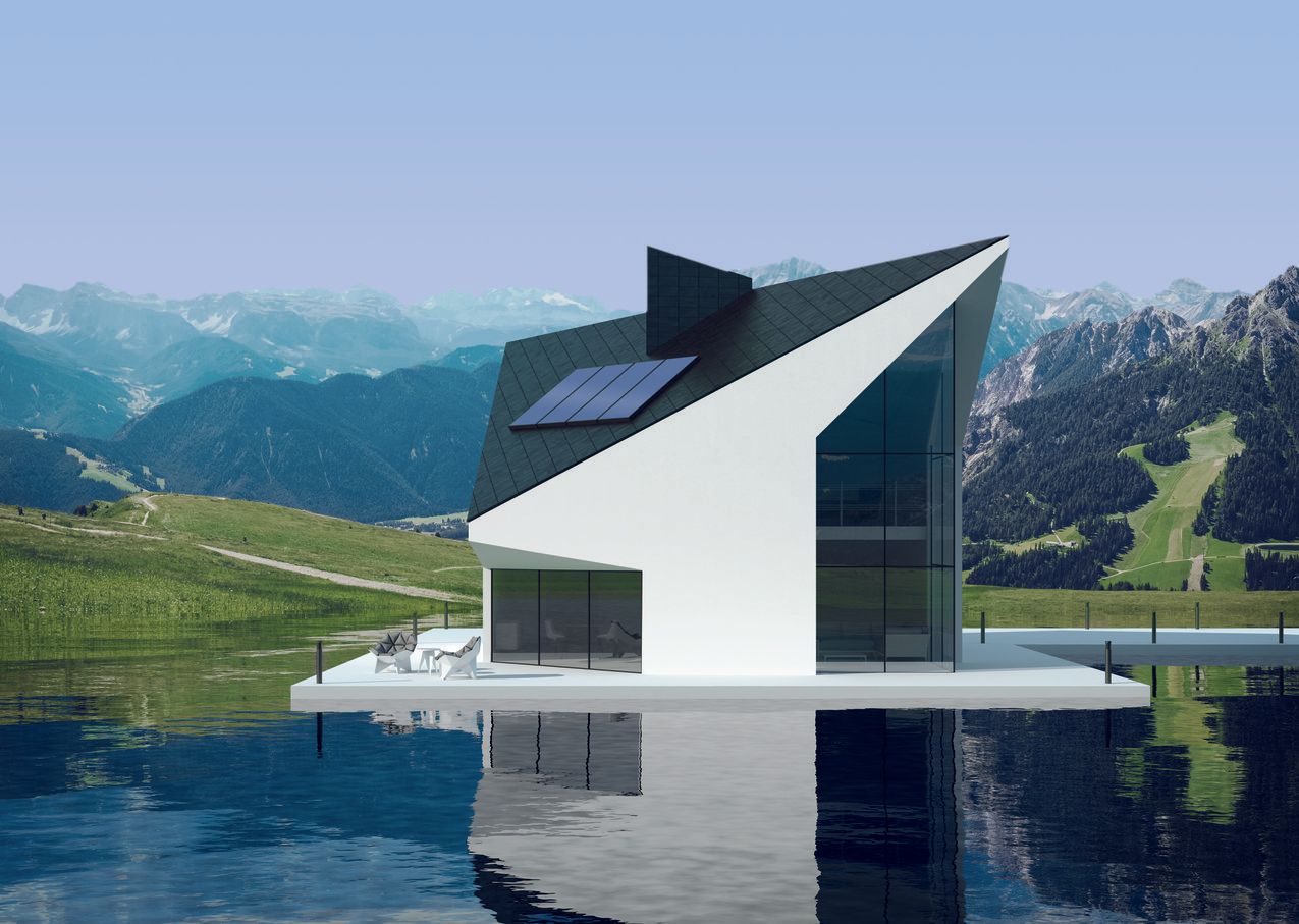 Ein modernes Haus steht auf einem See mit Bergen im Hintergrund.