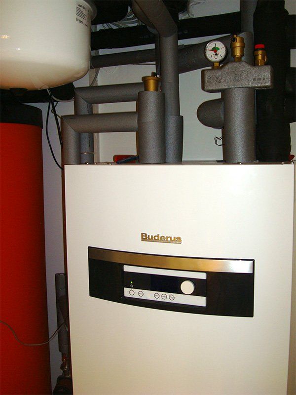 Ein Buderus-Kessel steht neben einem roten Tank