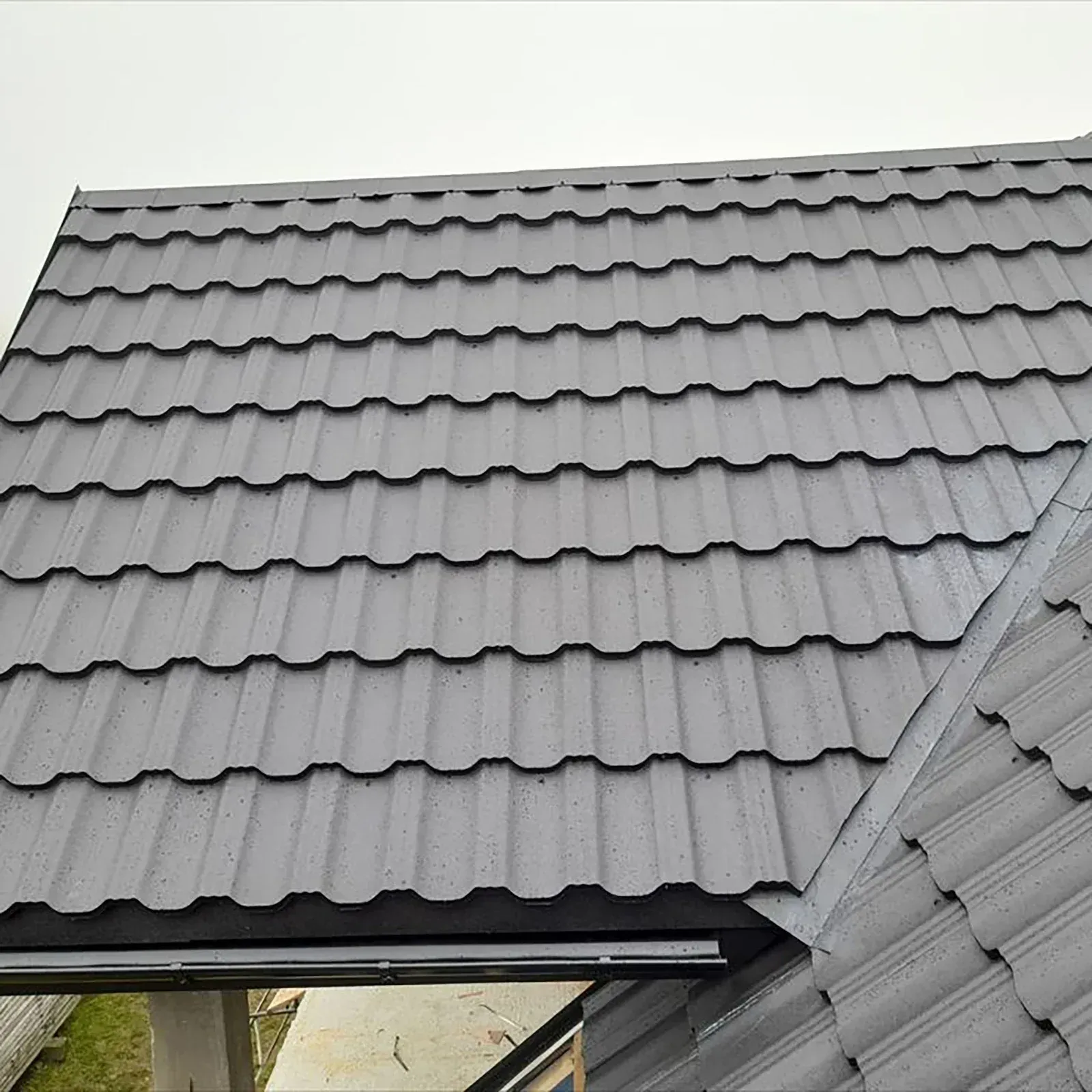 Gray metal roof tiles on a building, angled view.