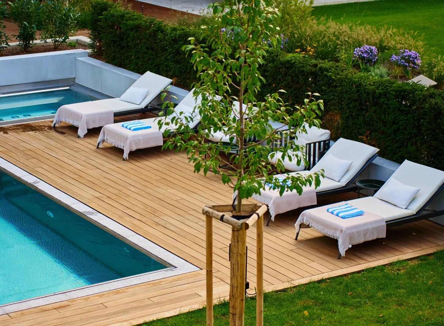 Two-story house with gray siding and garage doors, wet street, grass lawn, and dusk sky.
