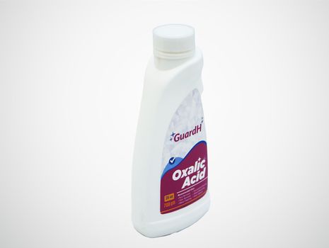 A bottle of oxalic acid is sitting on a white surface.