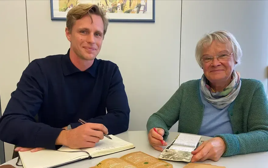 A man and a woman are sitting at a table with notebooks.