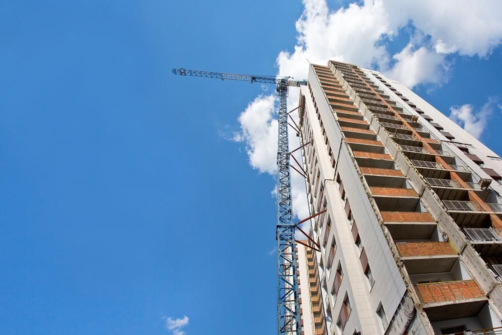 A Tall Building Under Construction With a Crane in Front of It — Cutting Edge Painting Contractors QLD in The Dawn, QLD