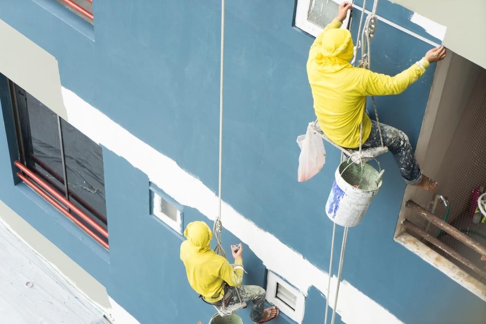 Two Men Are Painting a Building From a Rope — Cutting Edge Painting Contractors QLD in The Dawn, QLD