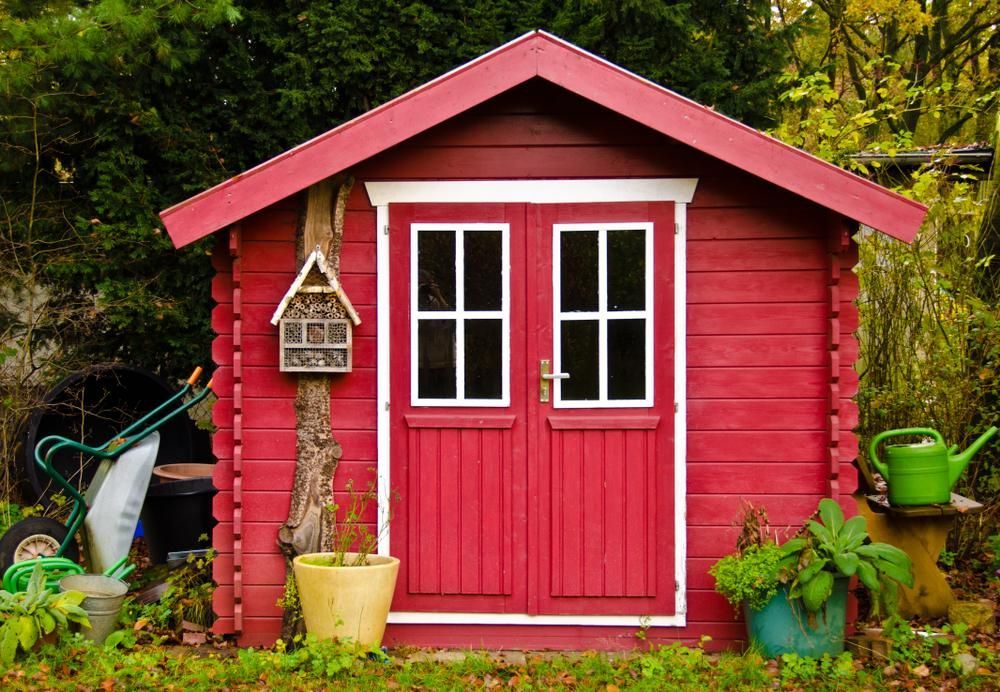 A Red Wooden Shed in a Garden With a Birdhouse and a Watering Can — Cutting Edge Painting Contractors QLD in The Dawn, QLD