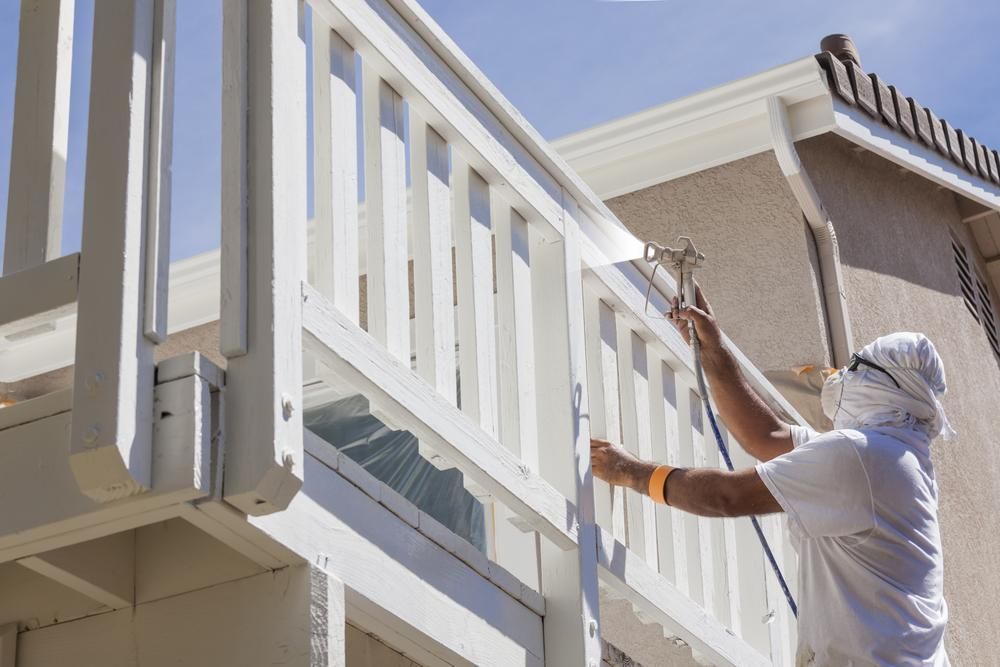 A Man is Painting a White Railing on a Balcony — Cutting Edge Painting Contractors QLD in The Dawn, QLD