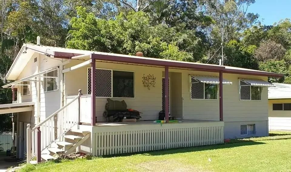 A Small White House With a Porch and Stairs — Cutting Edge Painting Contractors QLD in Goomboorian, QLD