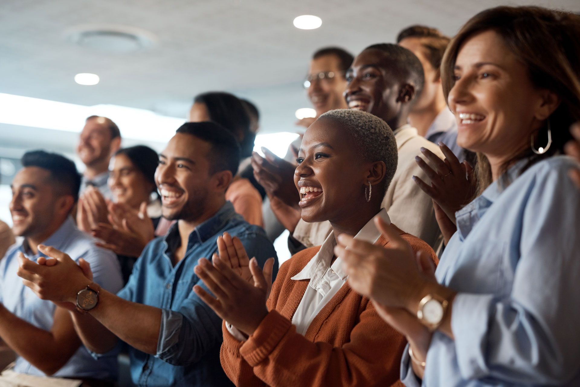 Group of people clapping and smiling in an office setting.