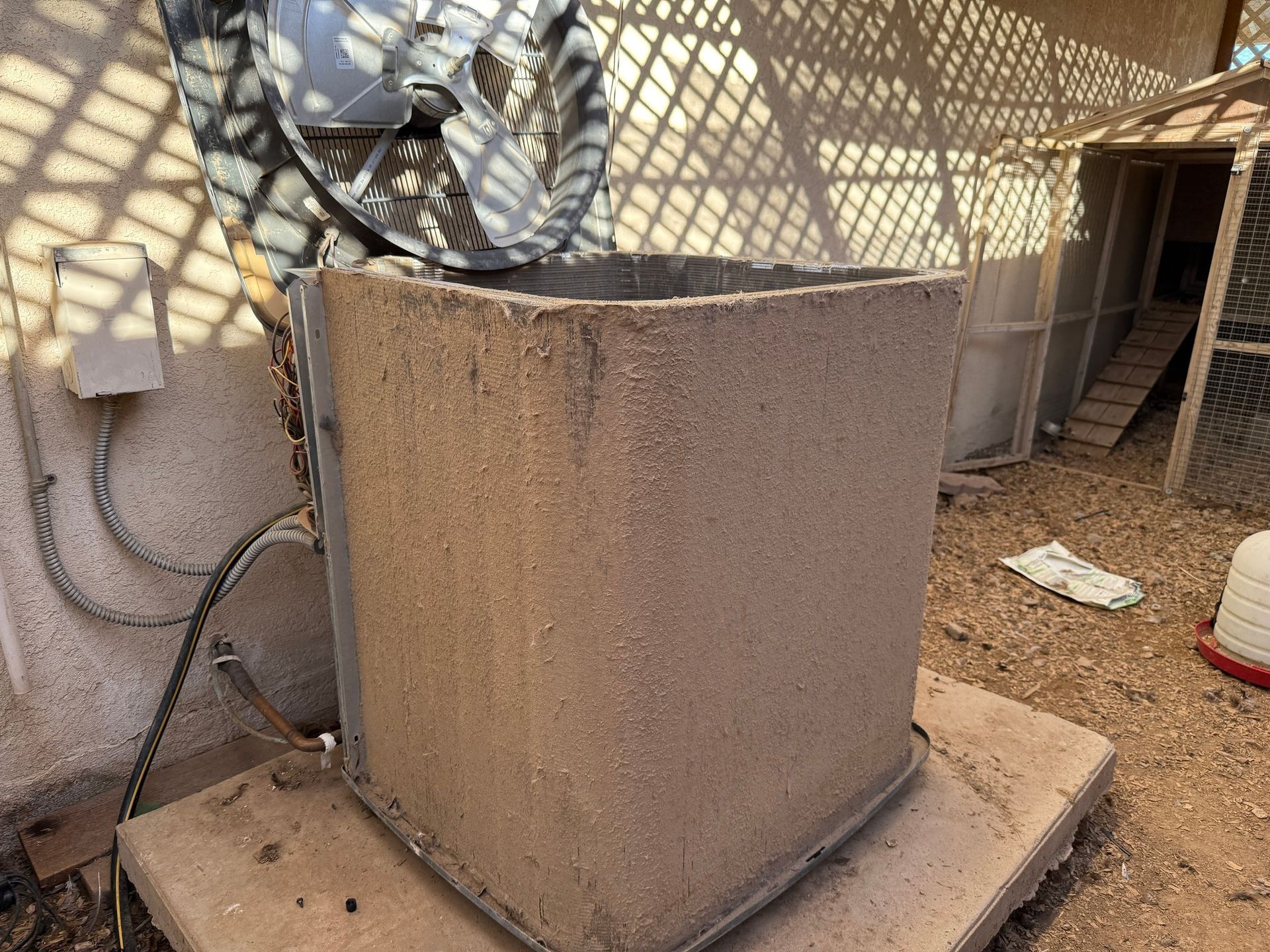 A weathered concrete box on a concrete pad with a hose reel above it; chicken coop in the background.