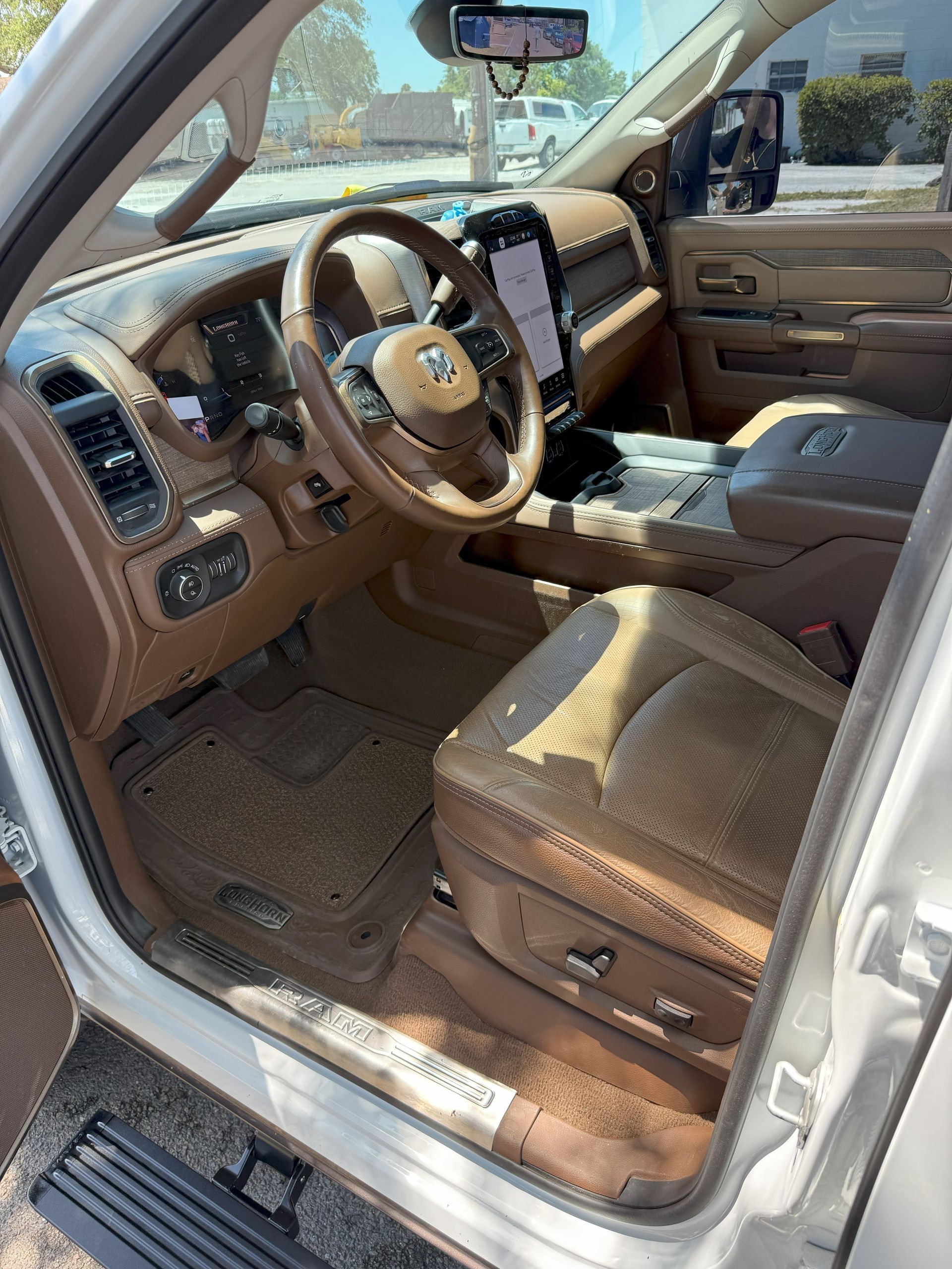 Interior view of a tan and brown Ram truck with leather seats, dashboard, and steering wheel.