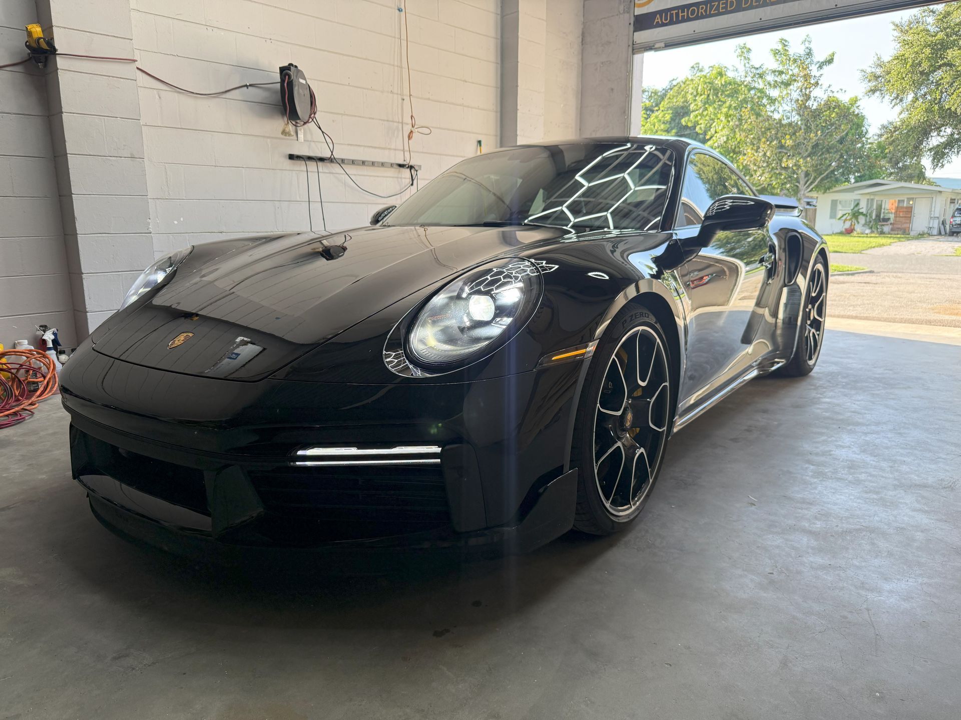 Black Porsche sports car parked inside a garage, shiny and new.