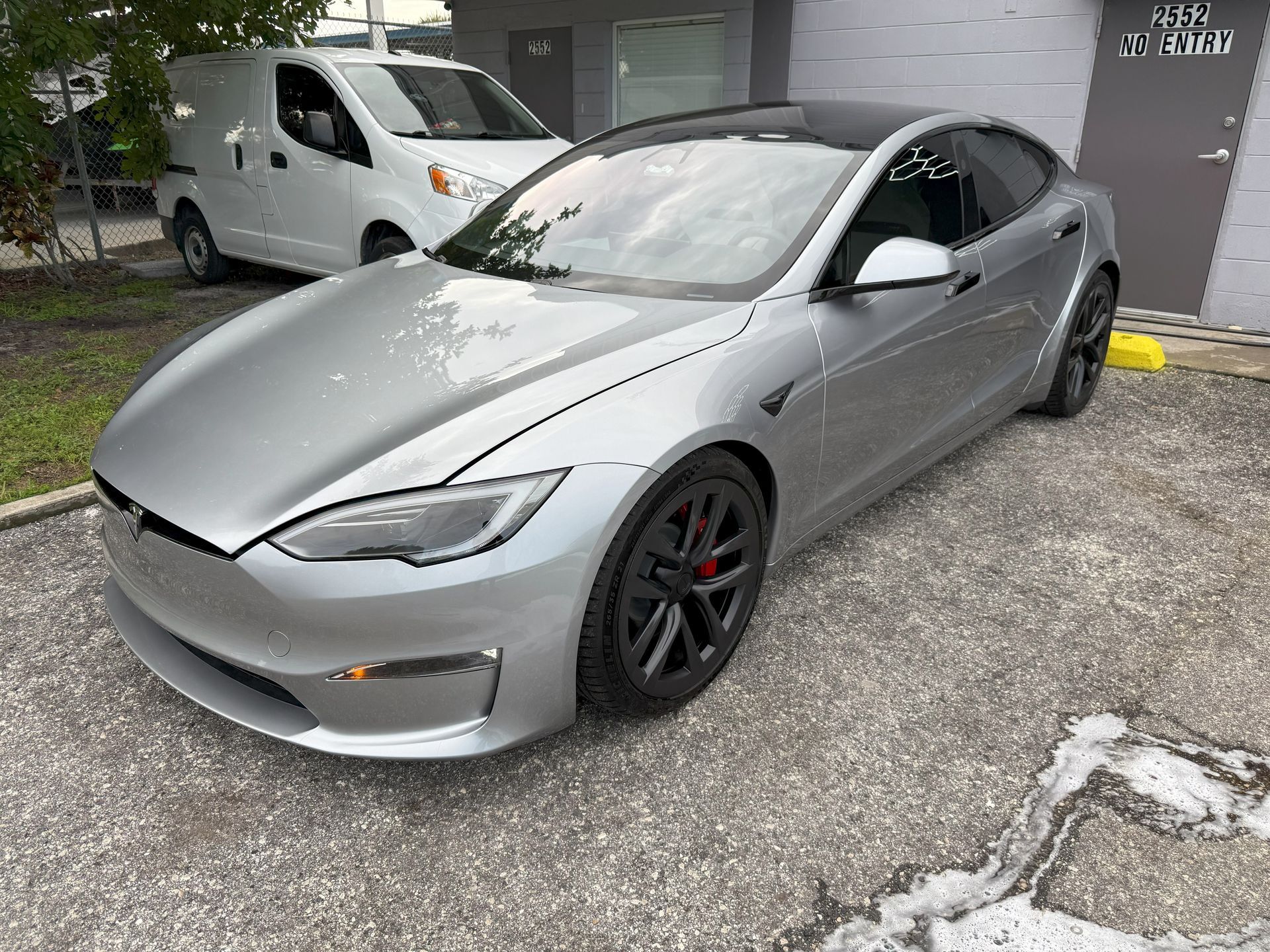 Silver Tesla car parked outside.
