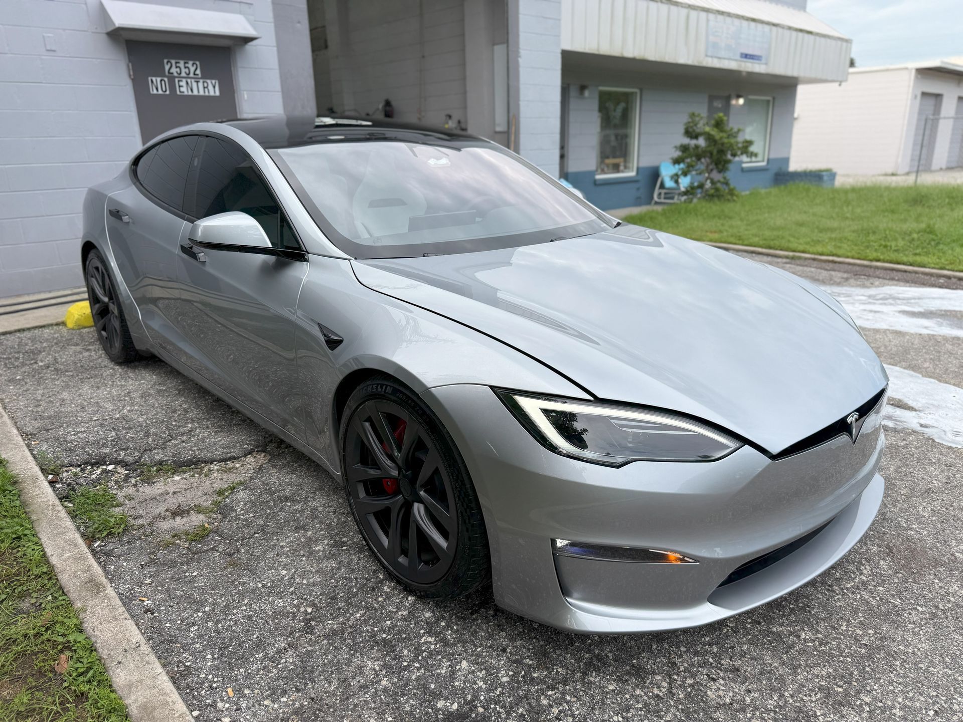 Silver Tesla Model S electric car parked outside a building.
