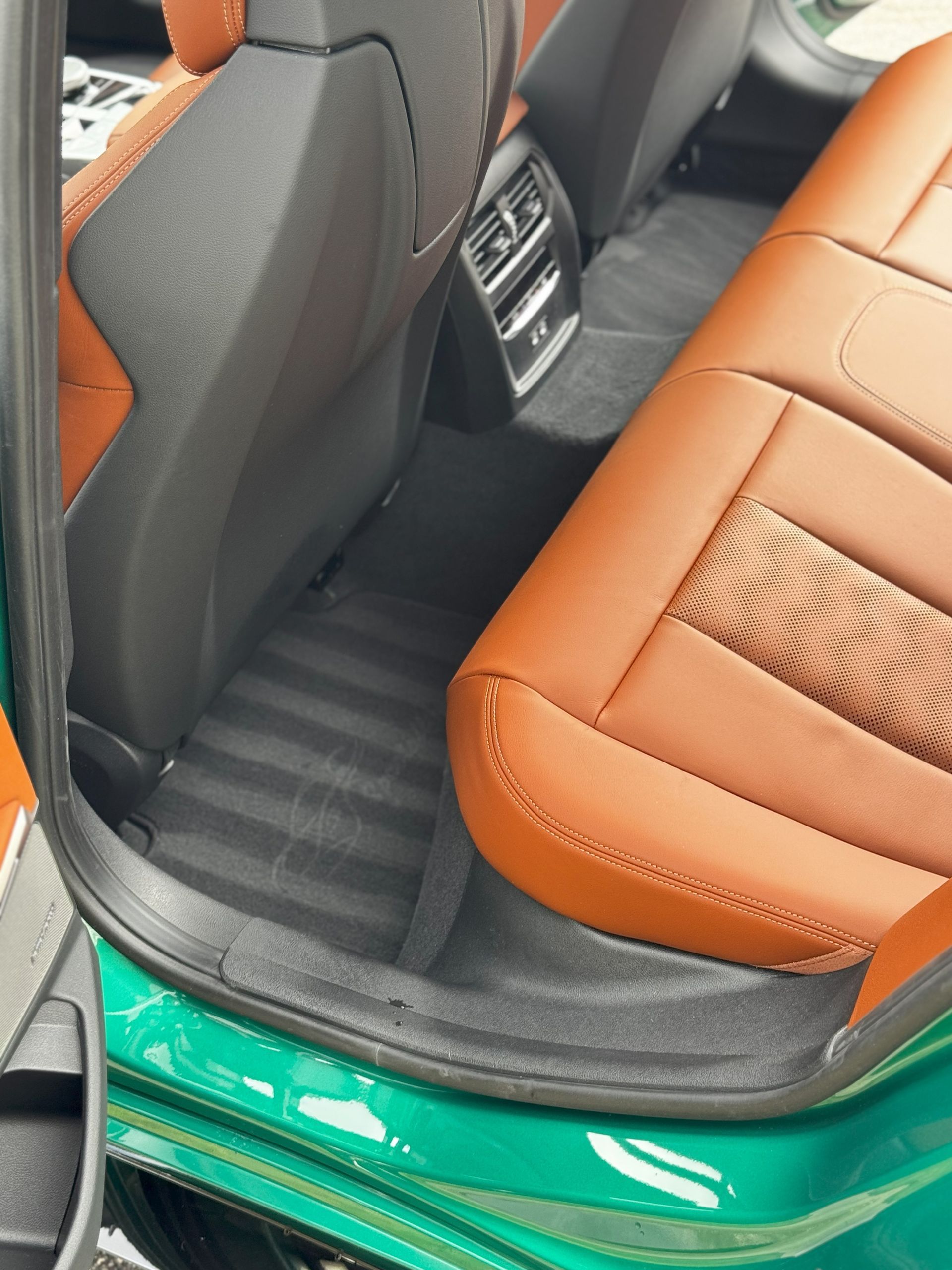 Car's interior with brown and black seats, cleaned floor. Green door frame.
