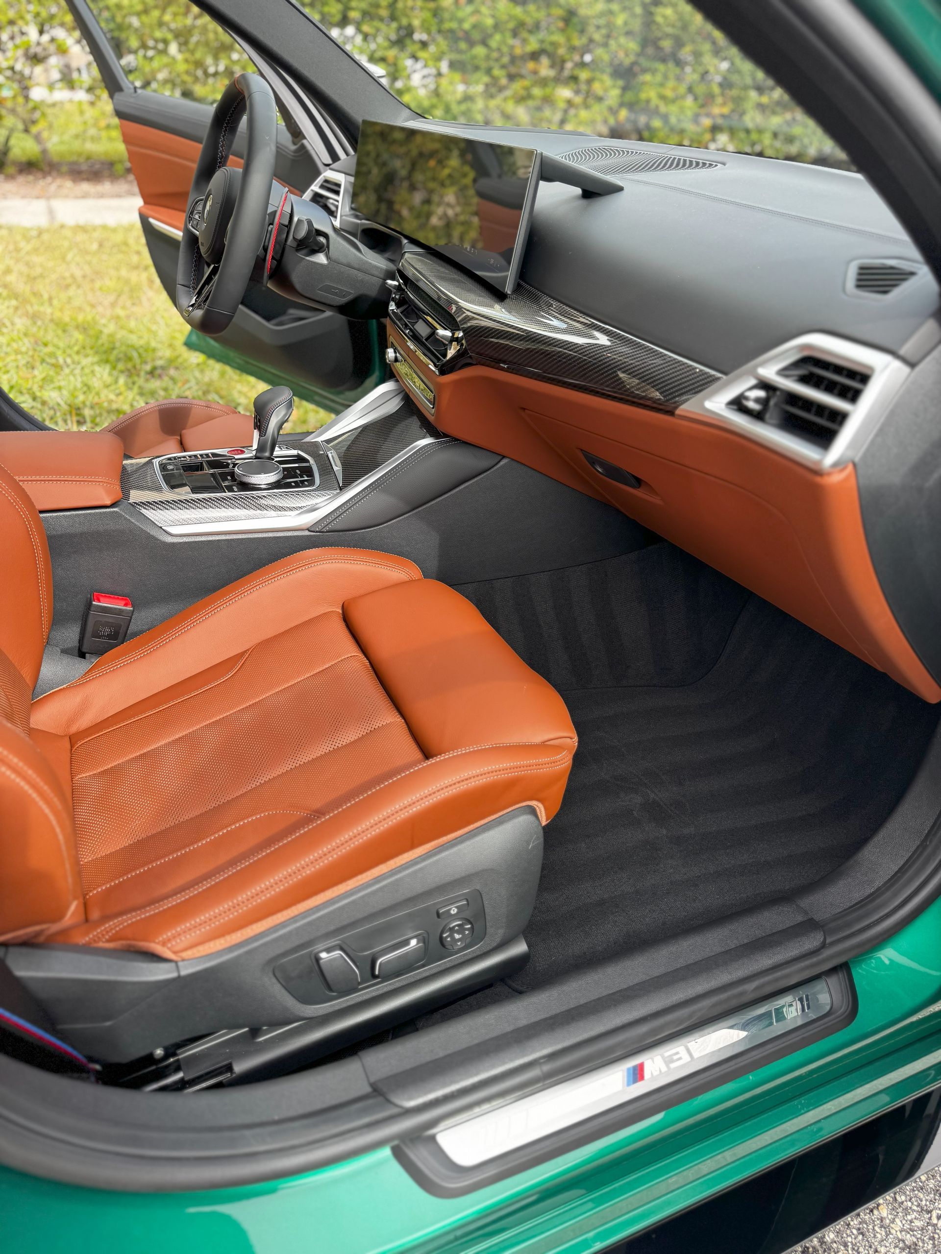 Green BMW interior with brown leather seats and carbon fiber trim.